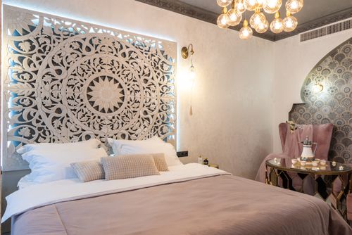 Free Bed with assorted pillows and ornamental wall against table with tea set illuminated by glowing lamps Stock Photo