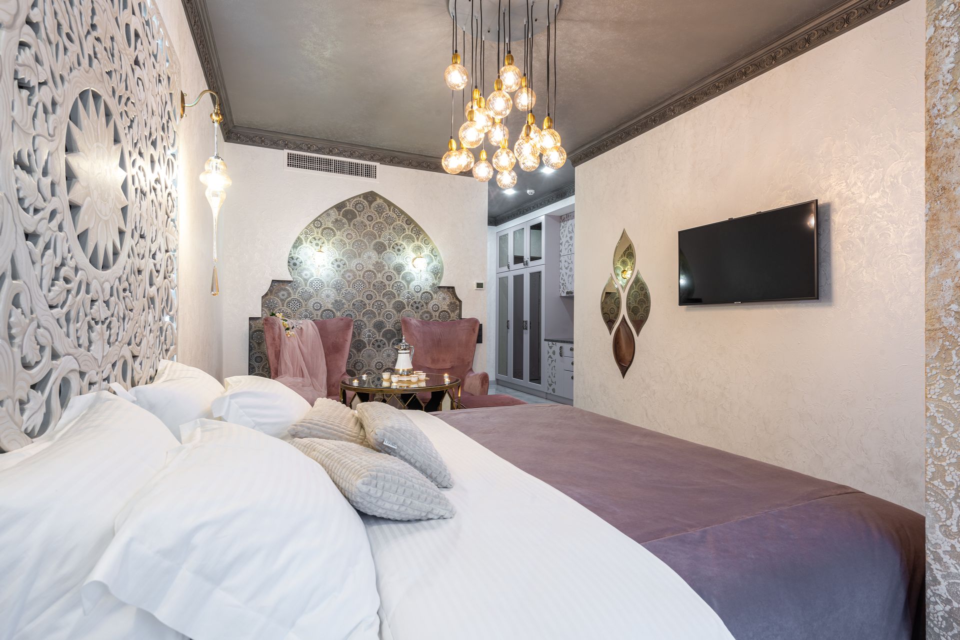 Bed with cushions against TV set and ornamental panel in house with shiny lights