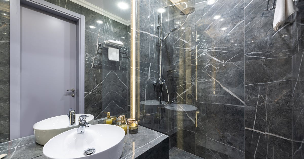 Shower cabin against washbasin and assorted hygiene products reflecting in mirror under luminous lamps at home
