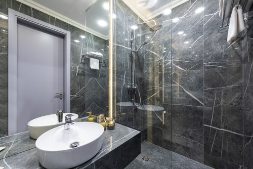 Free Shower cabin against washbasin and assorted hygiene products reflecting in mirror under luminous lamps at home Stock Photo