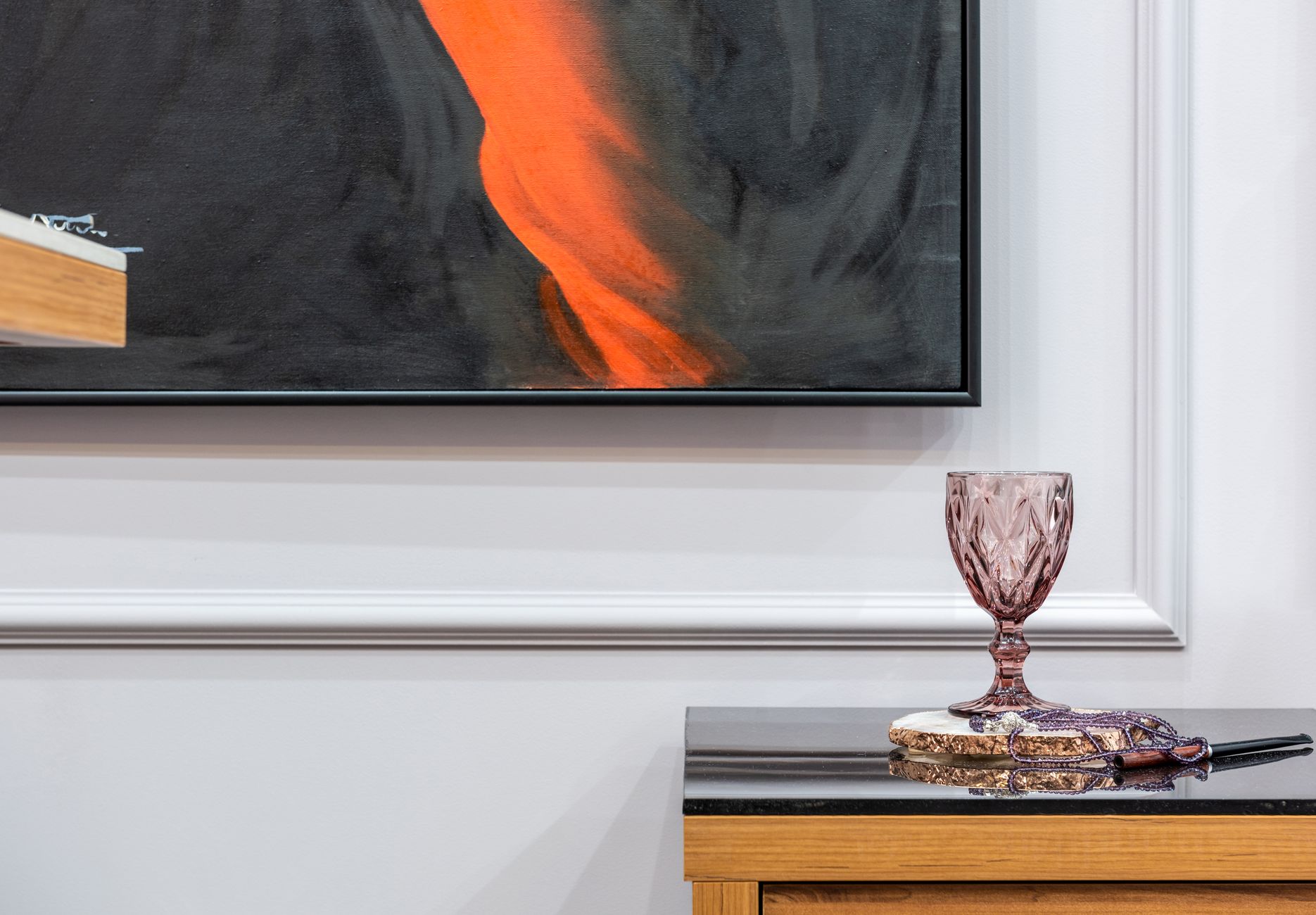 Glass with beads and mouthpiece reflecting on table against artwork on wall in house room
