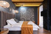 Soft bed with cushions and folded bathrobes under glowing lights in hotel room with decorative animal skull with horns