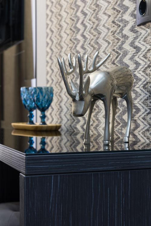 Free Animal statuette near ornamental glasses on tray reflecting on table against wall in room Stock Photo