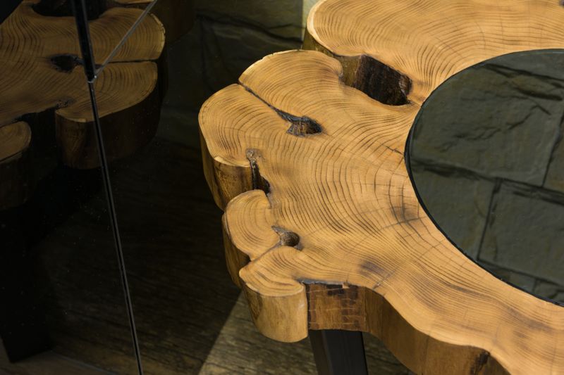 From above of wooden table with curved lines and spots on surface reflecting on glass wall