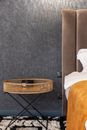 Bed with soft cover near carpet with straw tray table against gray wall at home
