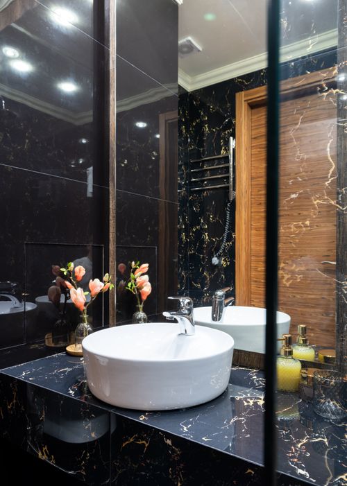 Free Washstand between bottle of liquid soap and floral decor against mirror under shiny lights in bathroom Stock Photo