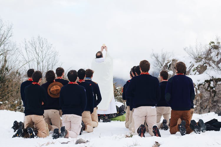 Group Of Men Praying In Snow During Mass