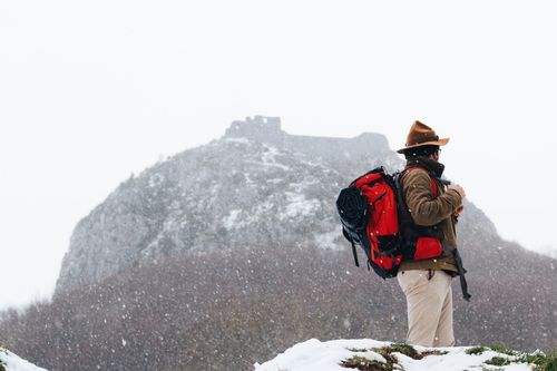 Free A man with a backpack exploring snowy mountains during winter snowfall. Stock Photo