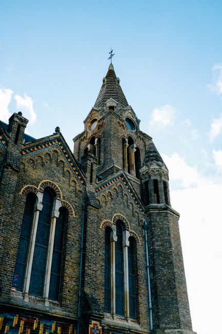 From below exterior of majestic historic church with ornamental details windows and rood on spire top