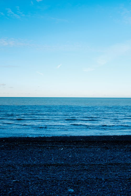 Peaceful blue sea washing black sandy coast