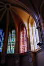 Low angle historic church dome with colorful leaded glass windows under arched ceiling in sunlight