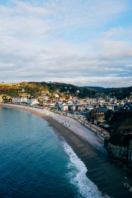 Picturesque scenery of typical residential houses located on hill slope near sandy beach washing by foamy waves of turquoise sea