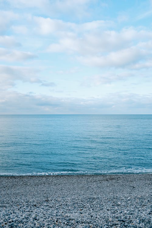 Free Picturesque scenery of vast peaceful blue sea under endless cloudy tranquil sky in daytime Stock Photo