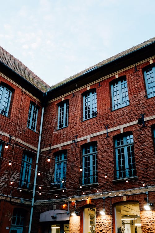 From below of exterior of aged brick building with bright lamps and luminous lights on garlands