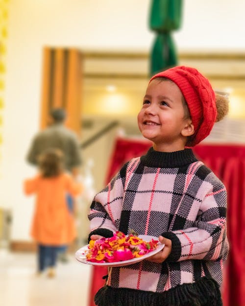 Photo of a Child in a Knitted Sweater Holding a Plate with Petals