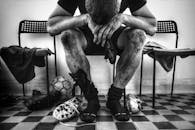 Man in Black Pants and Black and White Sneakers Sitting on Chair