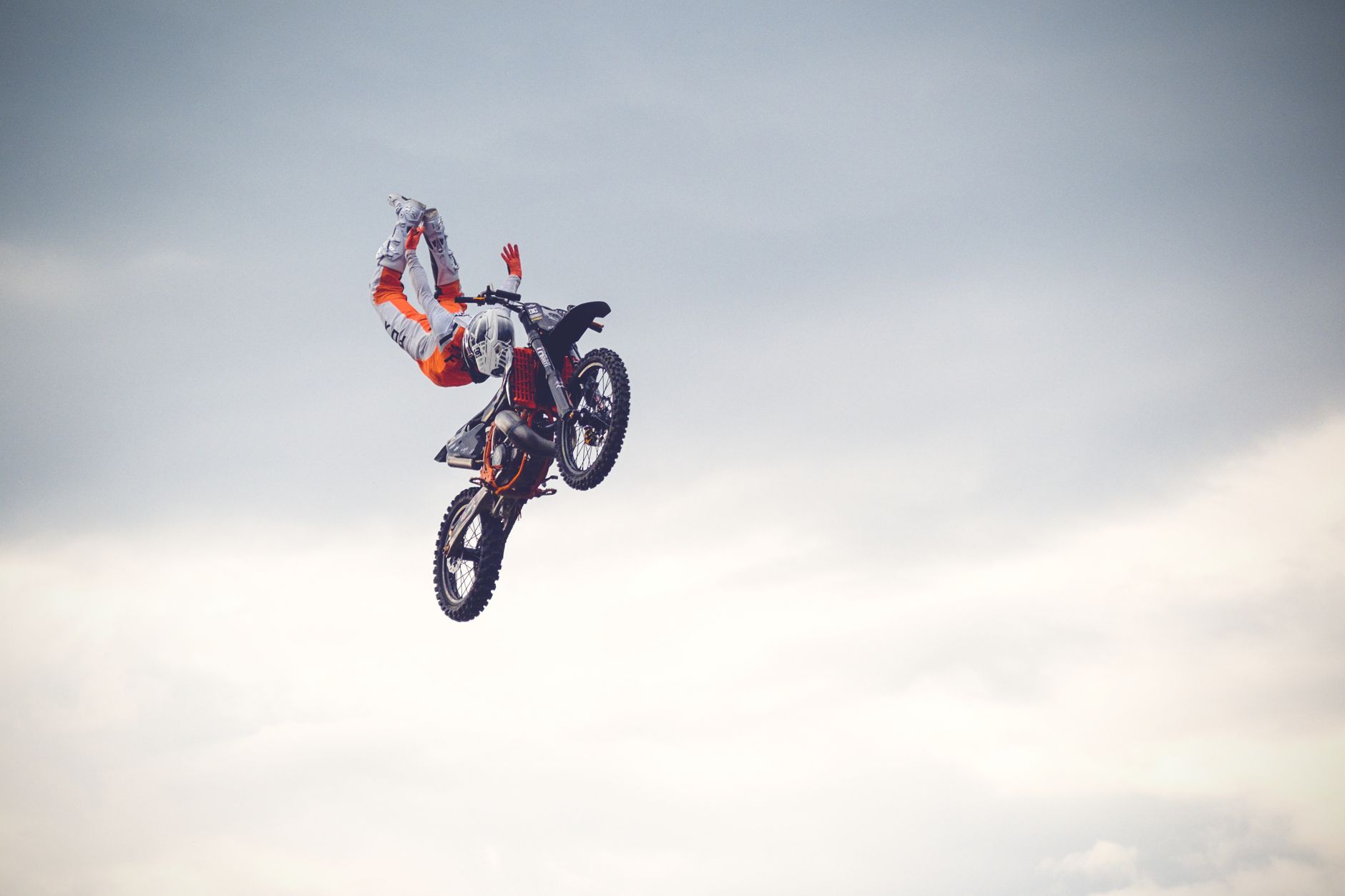 Motocross rider performs aerial stunt against a cloudy sky in Prague.