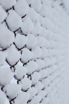 Detailed view of snow-covered metal fence creating geometric patterns in Estonia.