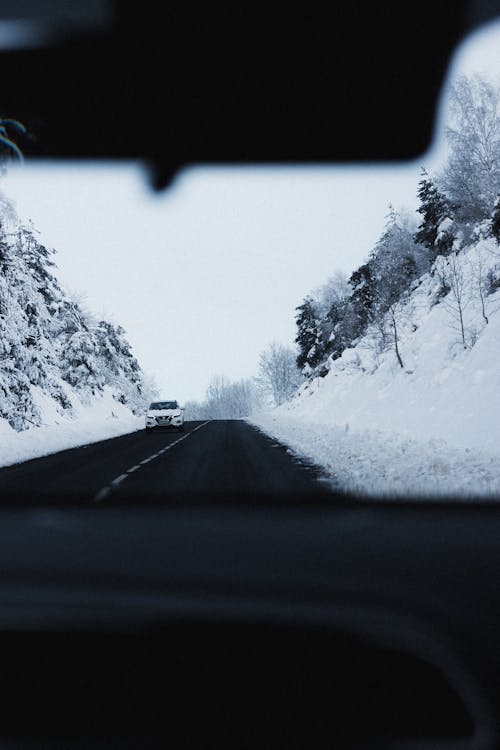 Car driving on road through snowy mountainous terrain