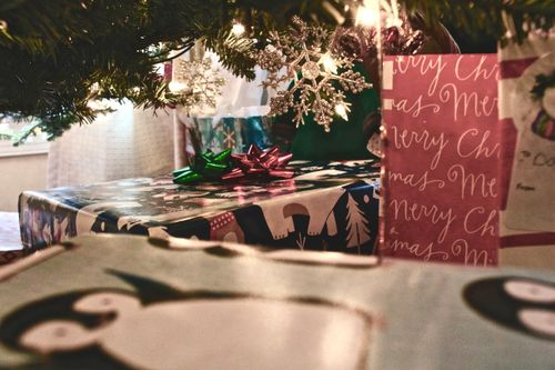 Free Christmas presents wrapped with festive decorations under a beautifully adorned tree, showcasing a cozy holiday atmosphere. Stock Photo