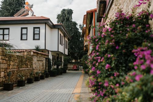 Free Serene residential alley with traditional houses, stone walls, and vibrant flowers in bloom. Stock Photo