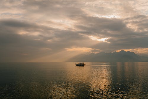 Picturesque scenery of boat floating on rippling water of sea against amazing cloudy sunset sky