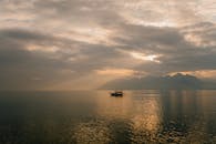 Ship sailing on sea under sundown sky