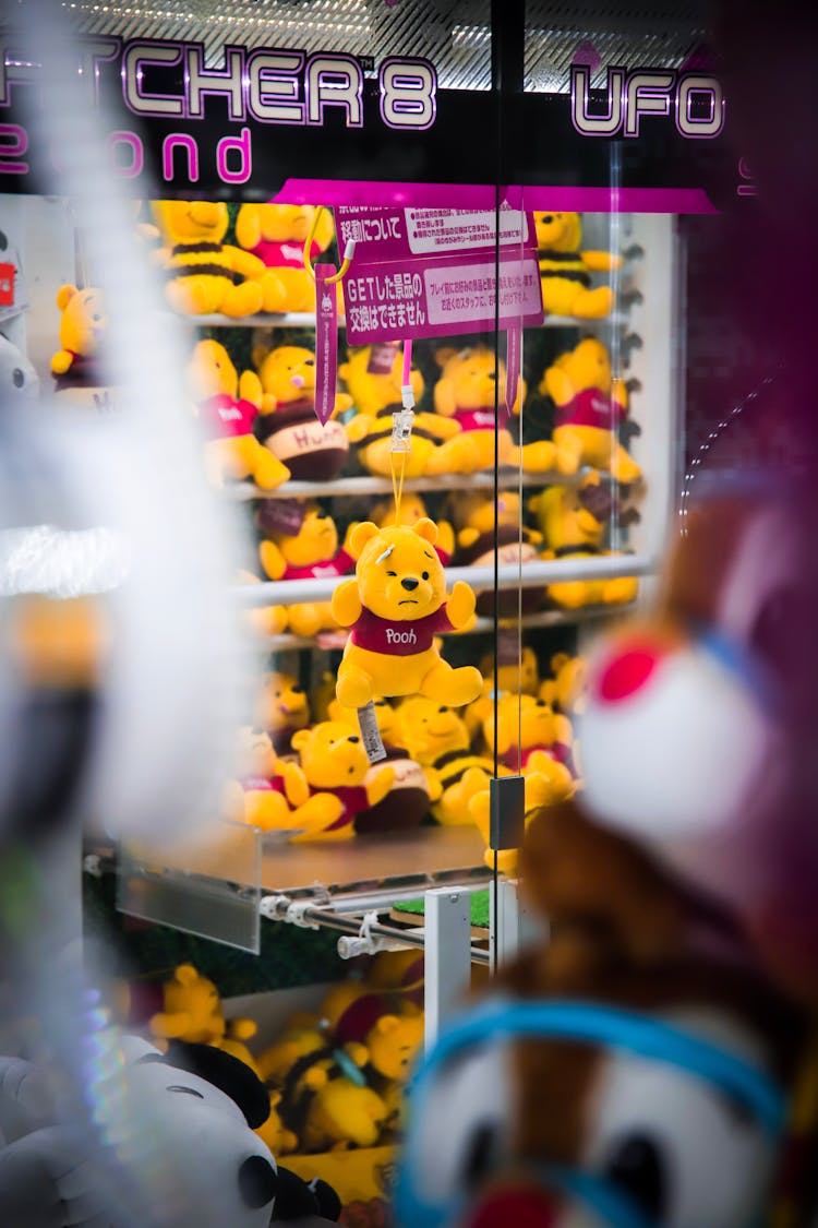 
An Arcade Machine With Winnie The Pooh Stuffed Toys