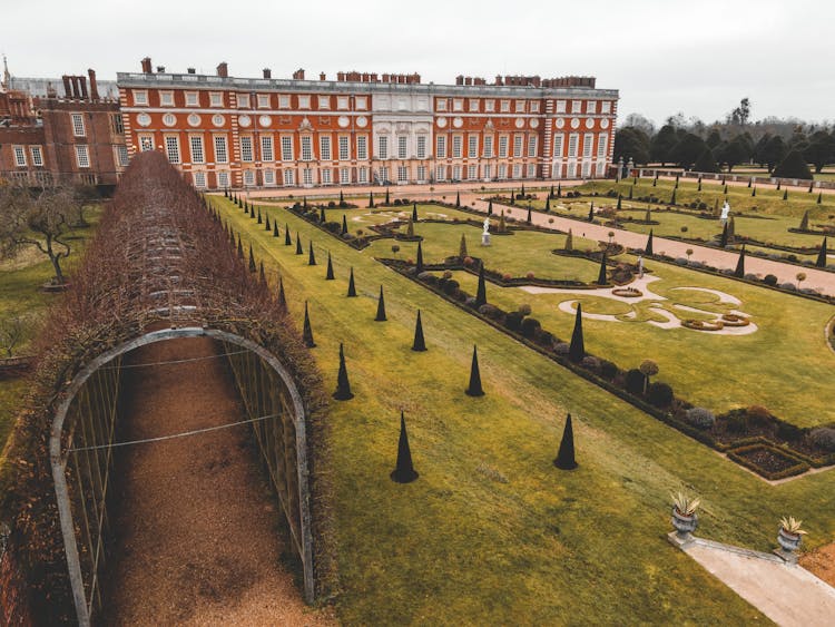 Historic Palace Near Grassy Lawn And Arched Passage In Yard