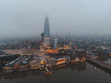 A dramatic aerial photo of London's skyline with the Shard standing through mist and fog.