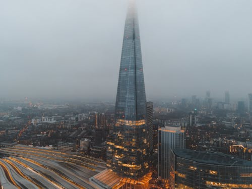 Aerial view of London city located in England with modern buildings and Shard skyscraper near railroads under gray cloudy sky in hazy day in daytime