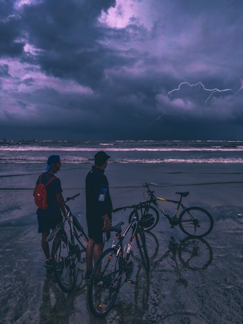 Free People with Bicycles on a Beach during a Thunderstorm Stock Photo