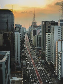 Discover the stunning aerial view of a vibrant city avenue lined with skyscrapers during sunset. Ideal for urban lifestyle content.
