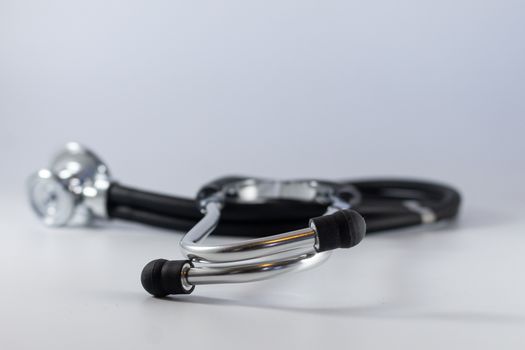 Detailed close-up of a medical stethoscope laying on a white surface with selective focus.