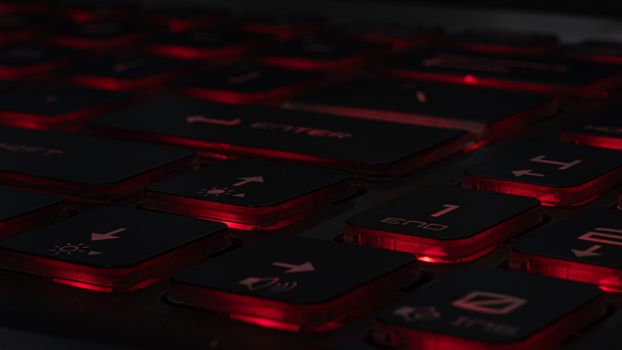 Detailed view of a backlit gaming keyboard with red LED lighting and black keys.