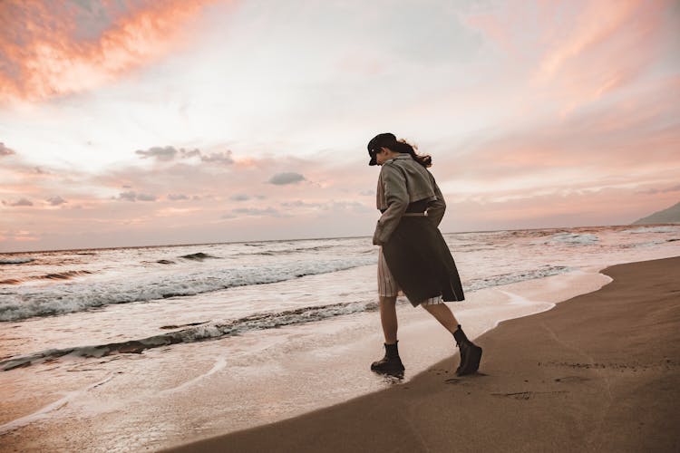 Woman In Coat Walking On Beach