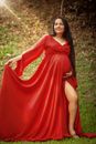 Full body of happy female in bright festive red dress smiling on lawn with fresh verdant grass in bright sunlight