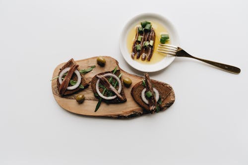 Sliced Bread with Green Olives and Anchovies on a Wooden Board