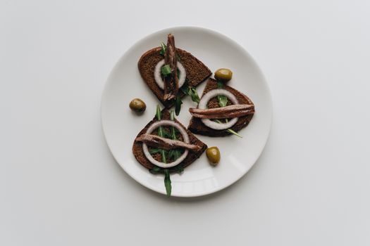 Savor this healthy dish featuring anchovy bruschetta with olives and fresh arugula.