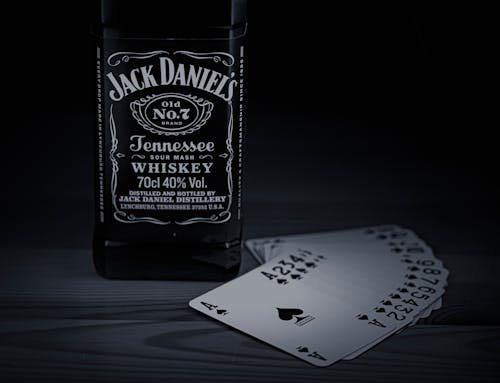 A Bottle of Jack Daniel's Liquor Beside Gaming Cards 