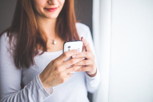 Free Close up portrait of a young woman typing a text message on mobile phone Stock Photo
