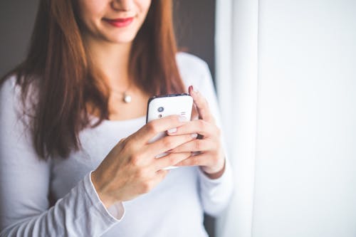 Close up portrait of a young woman typing a text message on mobile phone