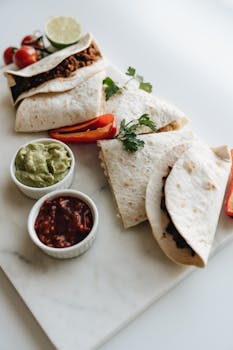 Delicious quesadillas served with guacamole and salsa on a marble board, perfect for lunch.