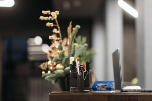 Free Office desk with holiday decorations, featuring a laptop, pens, and Christmas foliage. Stock Photo