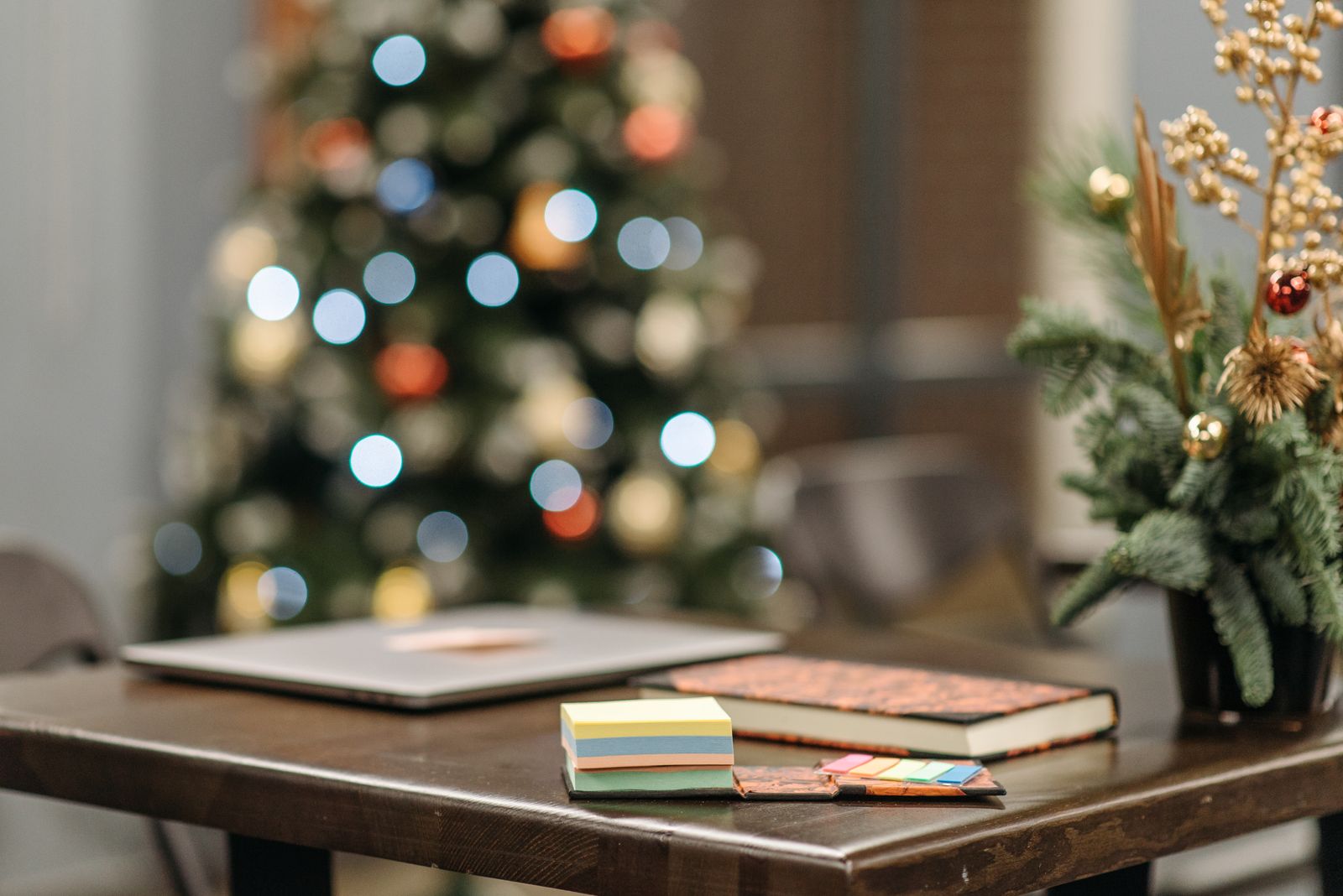 festive workspace with Christmas tree, book, and sticky notes, landscape