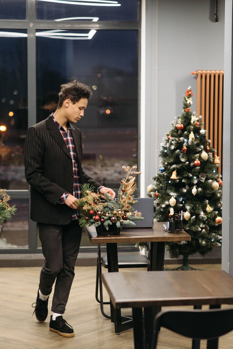 Man Standing By The Table And Touching A Christmas Decoration 