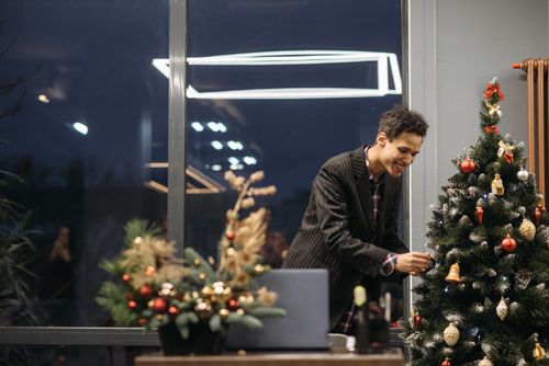 Free A cheerful man decorating a Christmas tree in a cozy indoor setting. Stock Photo