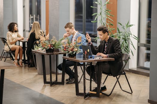 Two men in blazers working at a cafe with Christmas decorations on the tables.