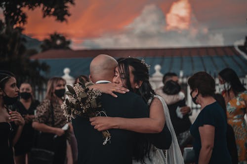 Free Romantic young newlyweds in classy wedding outfits hugging each other tenderly on street at twilight Stock Photo
