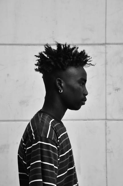 Black and white profile portrait of a young man with a unique hairstyle, exuding individuality.